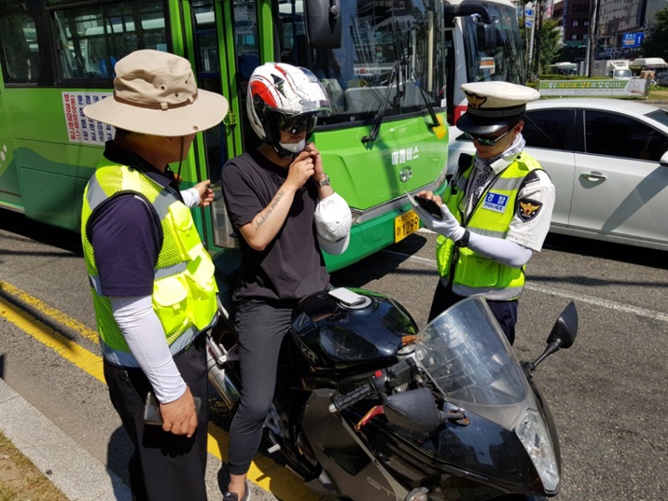 부산지방경찰청이 지난해 7월24일 서면 교차로에서 헬멧을 쓰지않은 이륜차 운전자에게 사고 예방을 위한 안전 헬멧을 무료로 전달하고 있는 모습. <사진제공=부산경찰청>